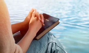 Person with the bible in front of the water