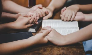 Hands together praying over the bible